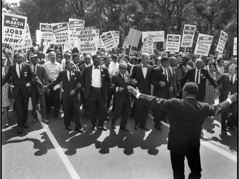 Civil rights leaders and demonstrators marching for racial equality during the 1960s, reflecting Raleigh's role in the Civil Rights Movement through activism, student protests, and community organizing.