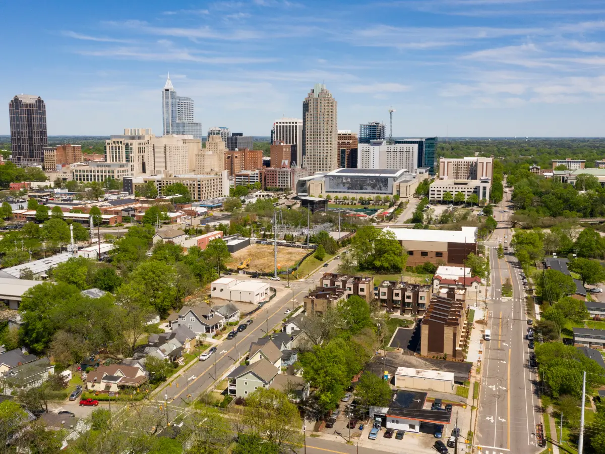 Panoramic aerial image of Raleigh, NC, showcasing downtown skyscrapers, historic neighborhoods, urban development, and the city landscape during daylight.